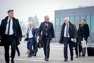 Bundeskanzler Friedrich Merz (CDU) geht zum Airbus A350 der Luftwaffe auf dem militärischen Teil der Flughafens BER Berlin-Brandenburg umringt von anderen Männern in Anzügen