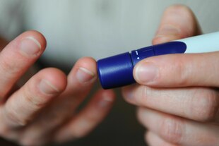 Eine Frau benutzt eine Stechhilfe für die Blutzuckermessung