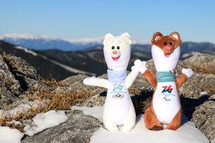 Zwei Maskottchen, Hermeline, dahinter Bergpanorama