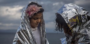 Zwei geflüchtete Mädchen auf Lesbos haben sie in wärmende Thermodecken gehüllt.