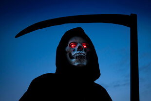 Ein als Sensenmann kostümierter Mensch mit Totenschädelmaske