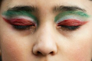 Frau mit geschlossenen Augen, die in den Landesfarben des Iran geschminkt sind