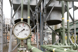 Gasspeicheranlage im Hintergrund und Druckmanometer der fast auf null ist im Vordergrund Gasspeicheranlage im Hintergrund und Druckmanometer der fast auf null ist im Vordergrund