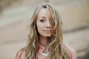 Eine Frau mit langen Haaren schaut freundlich in die Kamera