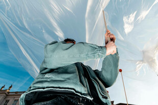 Eine Person bei einer Demonstration gegen Kulturkürzungen in Berlin schwenkt eine Fahne