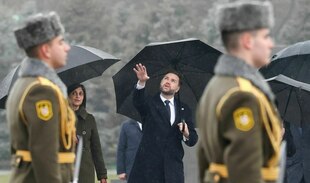 US-Vizepräsident JD Vance und seine Frau Usha Vance besuchen die armenische Völkermord-Gedenkstätte Zizernakaberd. Vance unter einem Regenschirm scheinbar verspult die Hand hebend, zwischen einer armenischen Ehrengarde gesehen