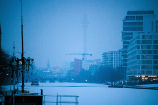 Eine geschlossene Eis- und Schneedecke liegt über der Spree. Darüber dichter Nebel, der den Berliner Fernsehturm verschwinden lässt