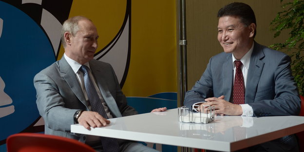 Kirsan Iljumschinow an einem Tisch mit Wladimir Putin.