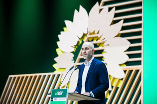 Belit Onay spricht auf der Bundesdelegiertenkonferenz der Grünen, den Kopf umrahmt von einer Sonnenblume.
