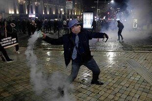 Ein Mann wirft eine Tränengasgranate zurück auf die Polizeikette