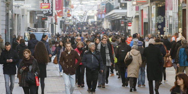 Menschen laufen eine Einkaufsstraße entlang.