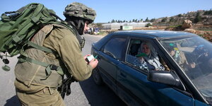 Ein israelischer Soldat kontrolliert ein Fahrzeug mit palästinenserInnen Insassen an einem Checkpoint nahe Hebron.