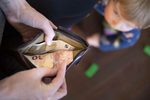 Blick auf einen Geldbeutel, in der Unschärfe ein Kind