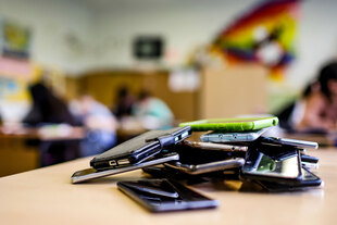 Etliche Mobiltelefone liegen auf einem Haufen in einem Klassenzimmer Etliche Mobiltelefone liegen auf einem Haufen in einem Klassenzimmer