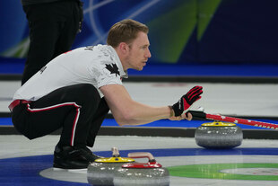 Ein Mann sitzt in der Hocke auf einer Eisbahn, sein Blick nach vorne fixiert Ein Mann sitzt in der Hocke auf einer Eisbahn, sein Blick nach vorne fixiert