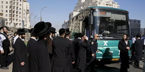 Orthodoxe Juden versammeln sich an der Bushaltestelle, an der die Philippinin verletzt wurde.