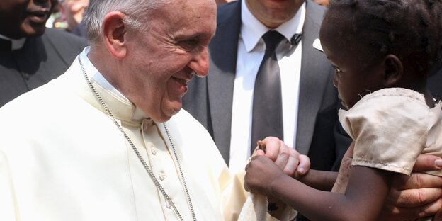 Papst Franziskus hält die Hand von einem kleinen Kind Papst Franziskus hält die Hand von einem kleinen Kind