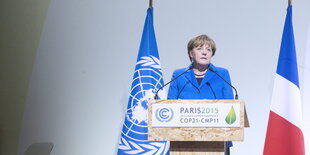 Angela Maerkel steht am Mikrofon und verkündet ihr Statement