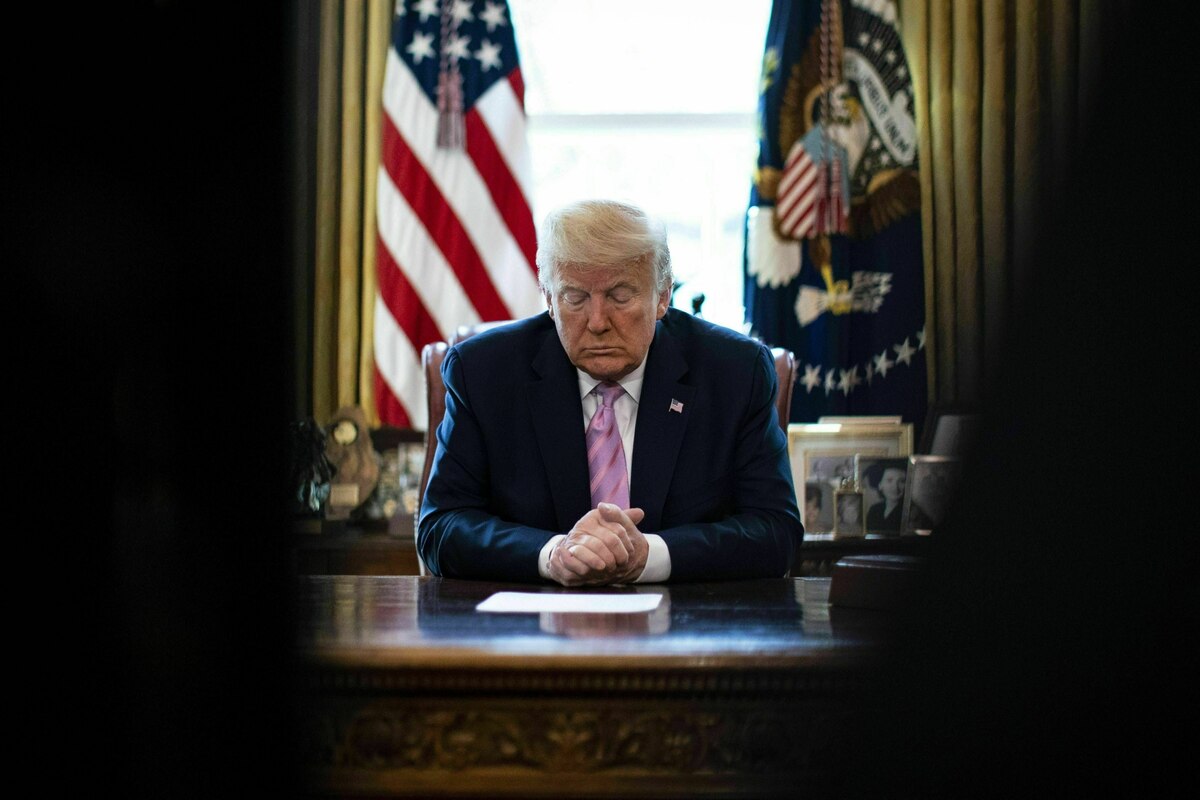 Donald Trump sitzt in seinem Büro und gibt sich andächtig