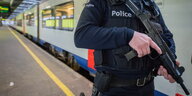 Ein Polizist steht mit Gewehr an einem Bahngleis
