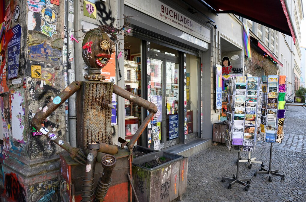 Eine lustige 'Skulptur' und Postkartenständer stehen vor dem Buchladen „Zur schwankenden Weltkugel“ in der Kastanienallee