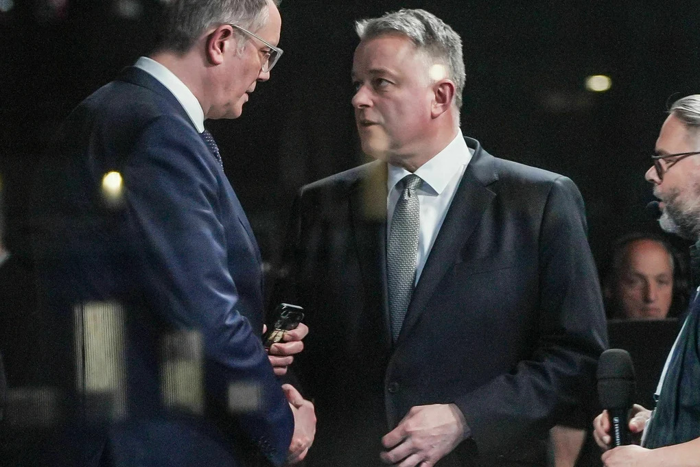 Ministerpräsident Alexander Schweitzer (l., SPD) gibt Wahlsieger Gordon Schnieder (CDU) im Fernsehstudio die Hand.