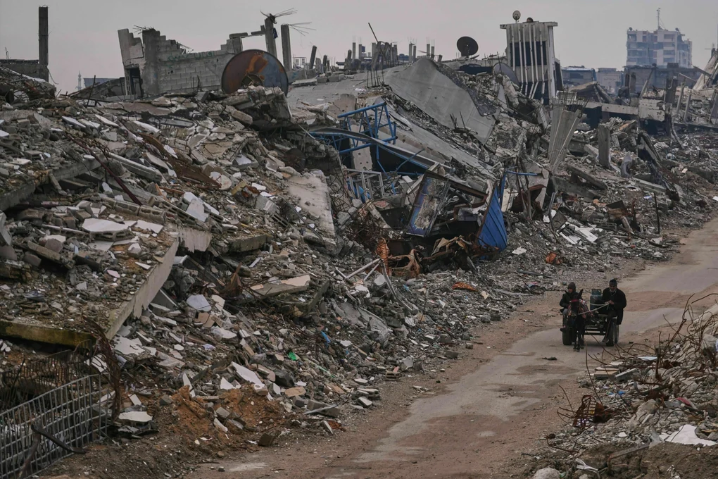 Palästinenser gehen eine Straße in der Stadt Gaza entlang, die von Gebäuden umgeben ist, die bei israelischen Luft- und Bodenangriffen im Viertel Sheikh Radwan zerstört wurden