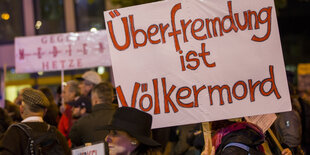 Demonstranten halten Plakat mit der Aufschrift: „Überfremdung ist Völkermord“