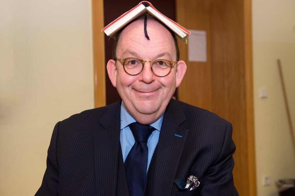 Ein glatzköpfiger Mann mit Buch auf dem Kopf