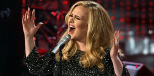 Adele singt mit ausgebreiteten Armen