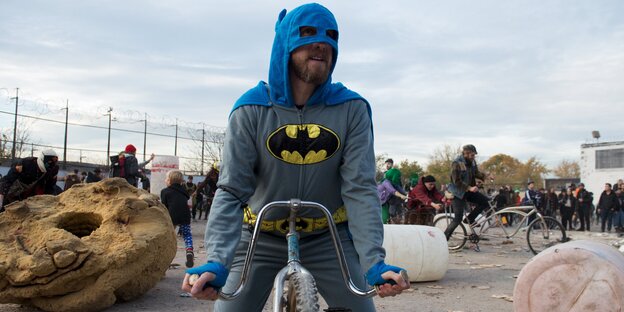 Ein Mann im Batman-Kostüm sitzt auf einem Fahrrad