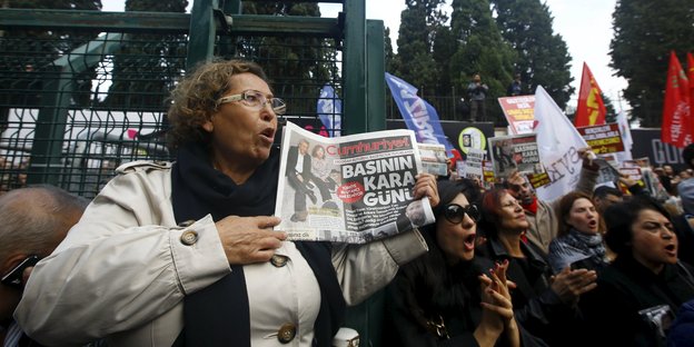Frau hält bei Demo eine Ausgabe der Cumhuriyet-Zeitung hoch.
