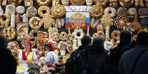Auf einer Messe in Moskau stehen Messehostessen vor prächtig gestalteten Backwaren