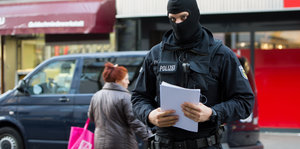 Vermummter Polizist trägt Stoß Papier