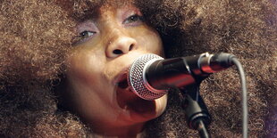 Erykah Badu mit viel Haar und Mikro