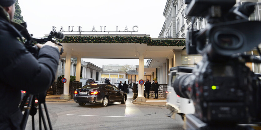 Der Eingang eines Hotels, ein Auto fährt vor, Kameras filmen das