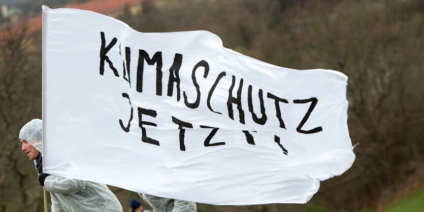 Demonstranten mit einer Fahne, auf der Klimaschutz jetzt steht.