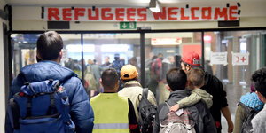 Flüchtlinge gehen am Flensburger Bahnhof unter einem Transparent 