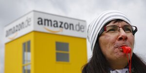 Eine Frau hat eine rote Trillerpfeife im Mund, hinter ihr ein Amazon-Logo