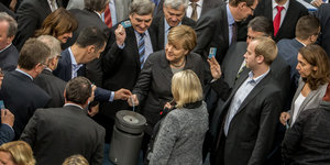Bundestagsabgeordnete werfen Stimmkarten in eine Urne