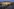 Die beleuchtete,gläserne Front des „Konzerthauses am Schloss“ bei Dämmerung, fotografiert von einem gepflasterten Vorplatz aus unter einem weiten, dunkelblauen Himmel.