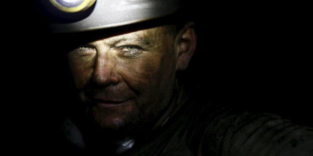 Ein polnischer Minenarbeiter schaut in die Kamera, sein gesicht ist mit Kohle verschmiert