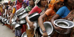 Frauen stehen mit leeren Schalen für Essen an.