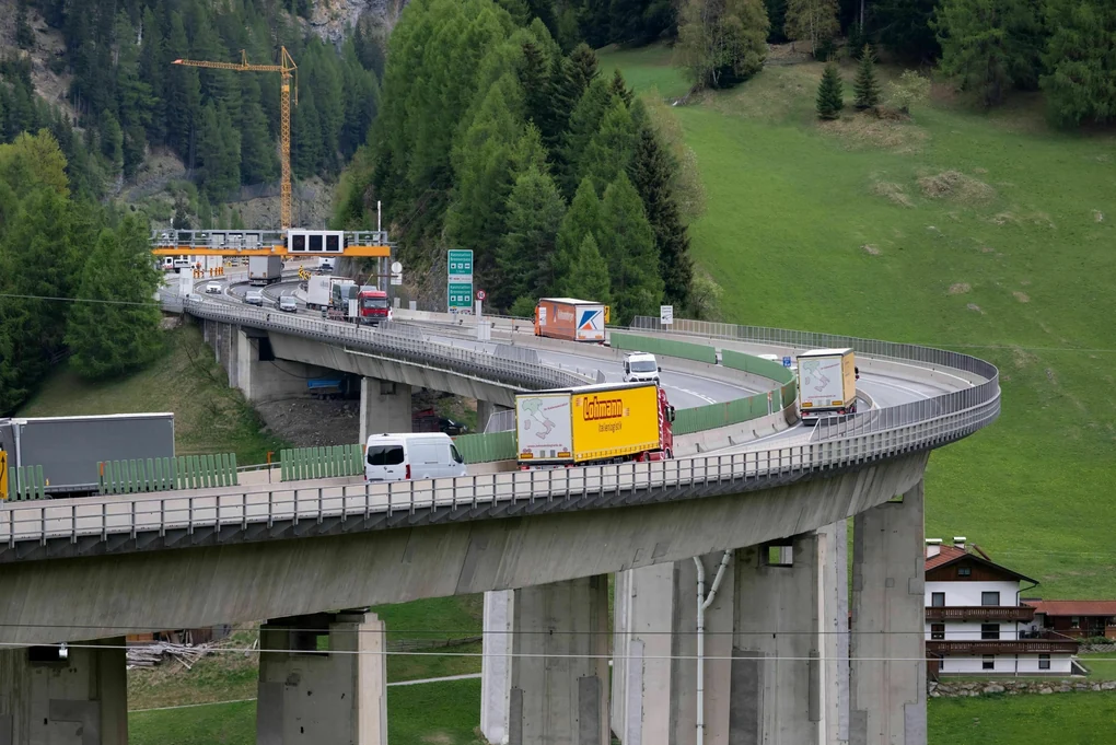 Brennerautobahn mit Autos und Lastwagen , die Brücke führt oberhalb eines Hauses