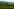 Eine hügelige Landschaft mit Weinbergen und Wiesen, im Hintergrund eine bläuliche Bergkette.