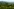 Eine hügelige Landschaft mit Weinbergen und Wiesen, im Hintergrund eine bläuliche Bergkette.