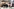 Vier Personen sitzen und stehen an einem Tisch mit zwei Laptops und einer Kamera, im Hintergrund Regale mit Ordnern und ein Banner mit der Aufschrift 'UnAuf'.