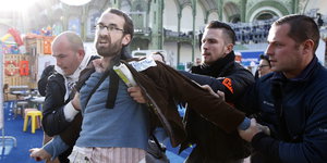 Ein Protestant wird von drei Sicherheitskräften abgeführt