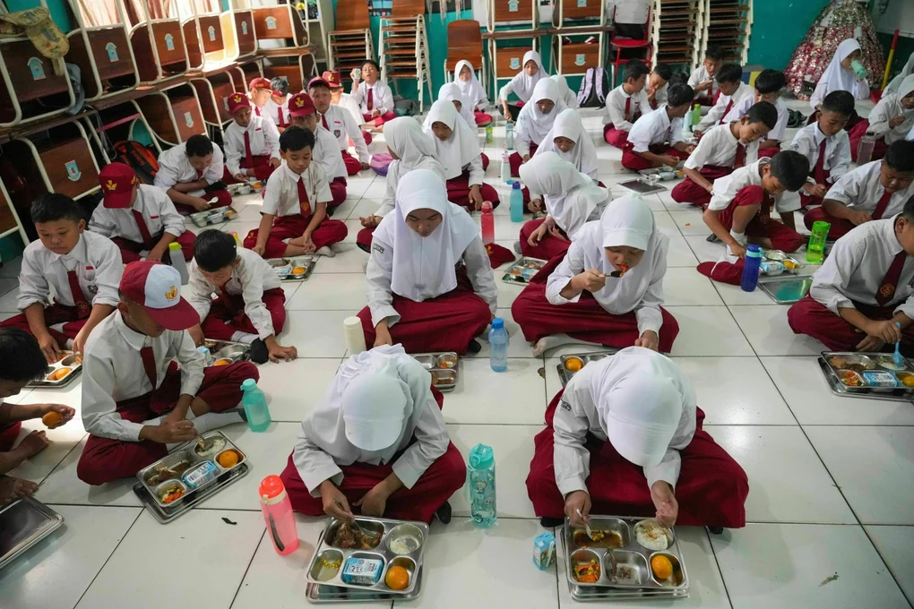 Indonesische Schüler:innen sitzen auf dem Boden vor ihrem Mittagessen