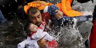 Ein Mann mit Schwimmweste steht im Wasser und hält ein Baby und ein Kleinkind im Arm